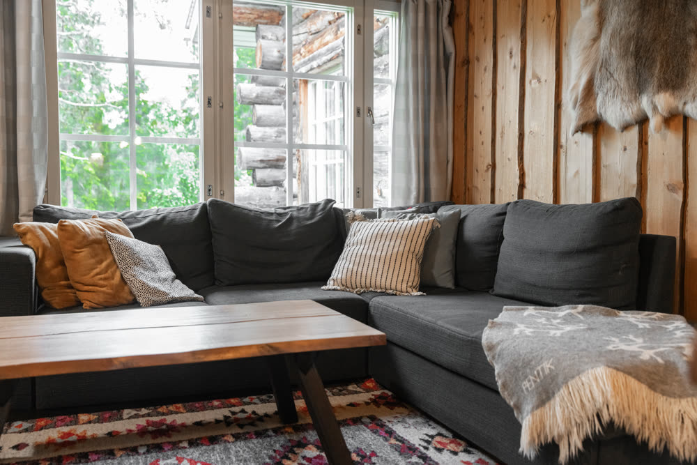 Living room with reindeer hide, dark sectional sofa and log walls